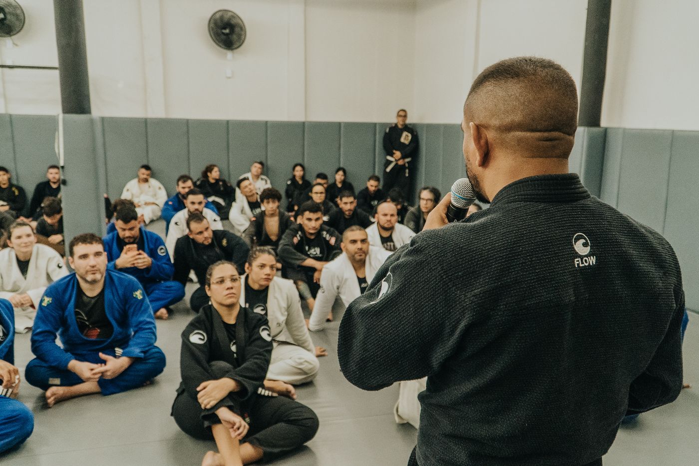 Professor da Flow conduzindo a aula para a turma sentada no tatame